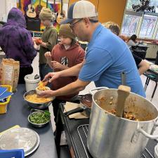 A teacher and elementary students prepare food in a commercial kitchen